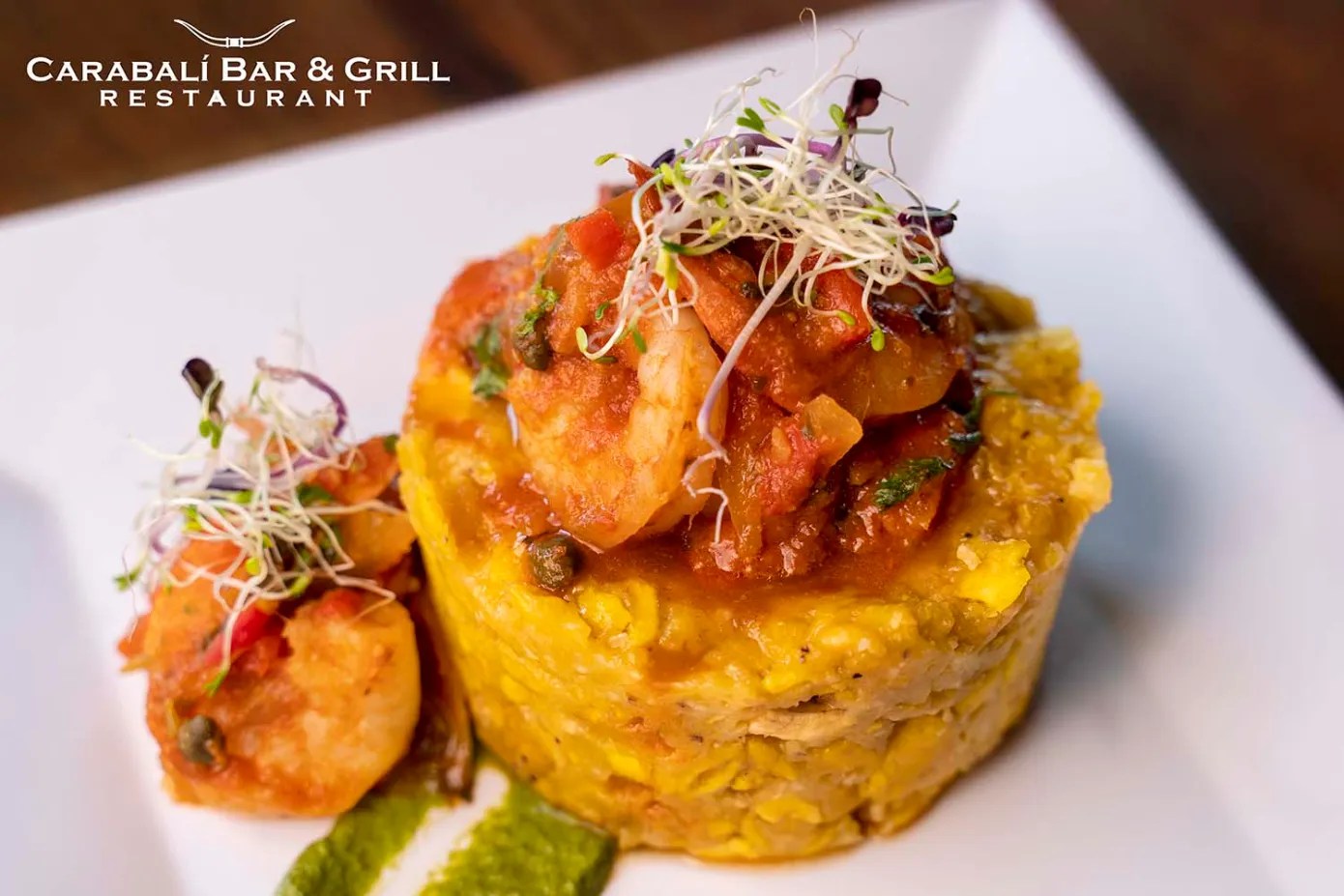 Plate of mofongo with shrimp and sprouts on a white plate.