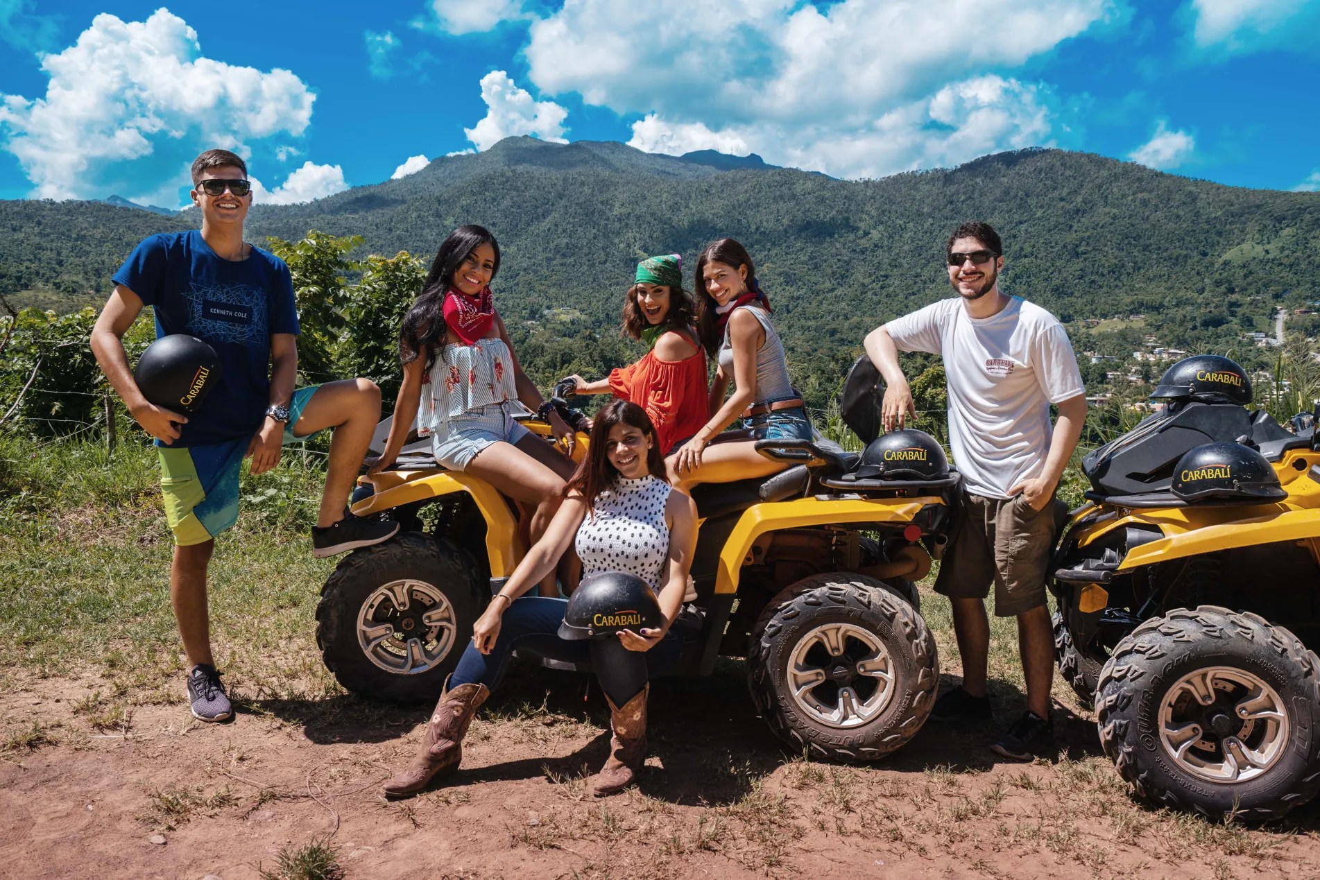 Group of people with ATVs in a scenic mountain area under a blue sky.